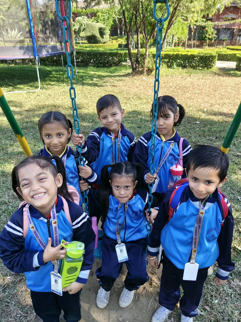 Five MGM pupils smiling beside a playground swing