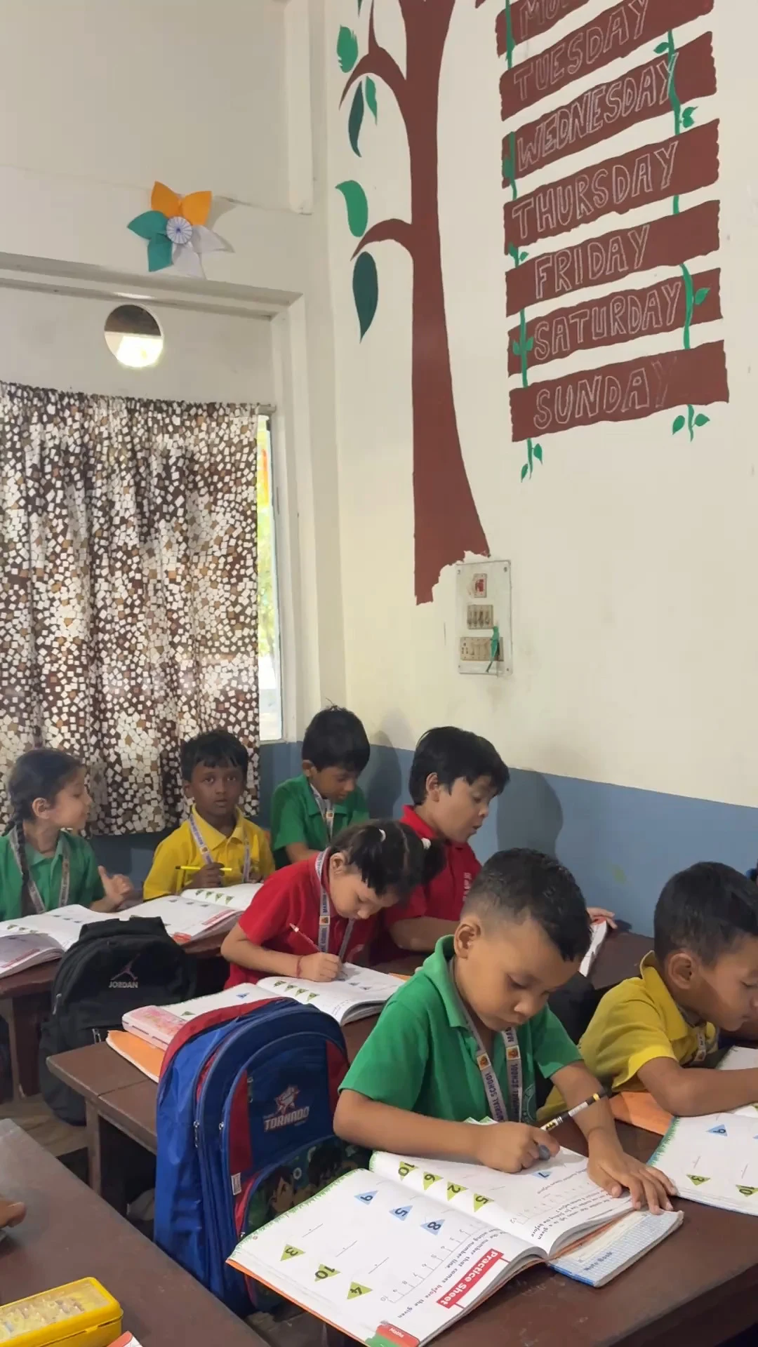 Students seated at desks writing in practice notebooks