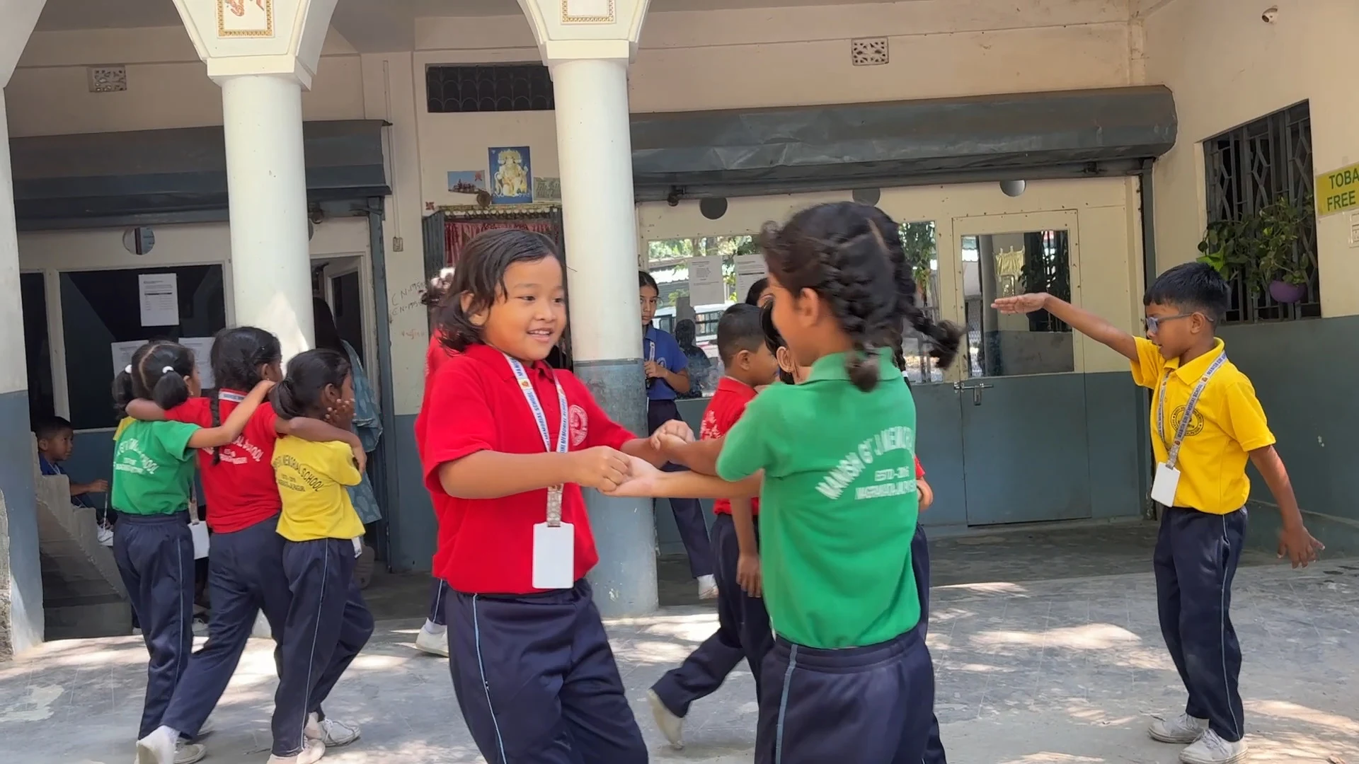 Students holding hands and playing outdoor circle games in the school courtyard