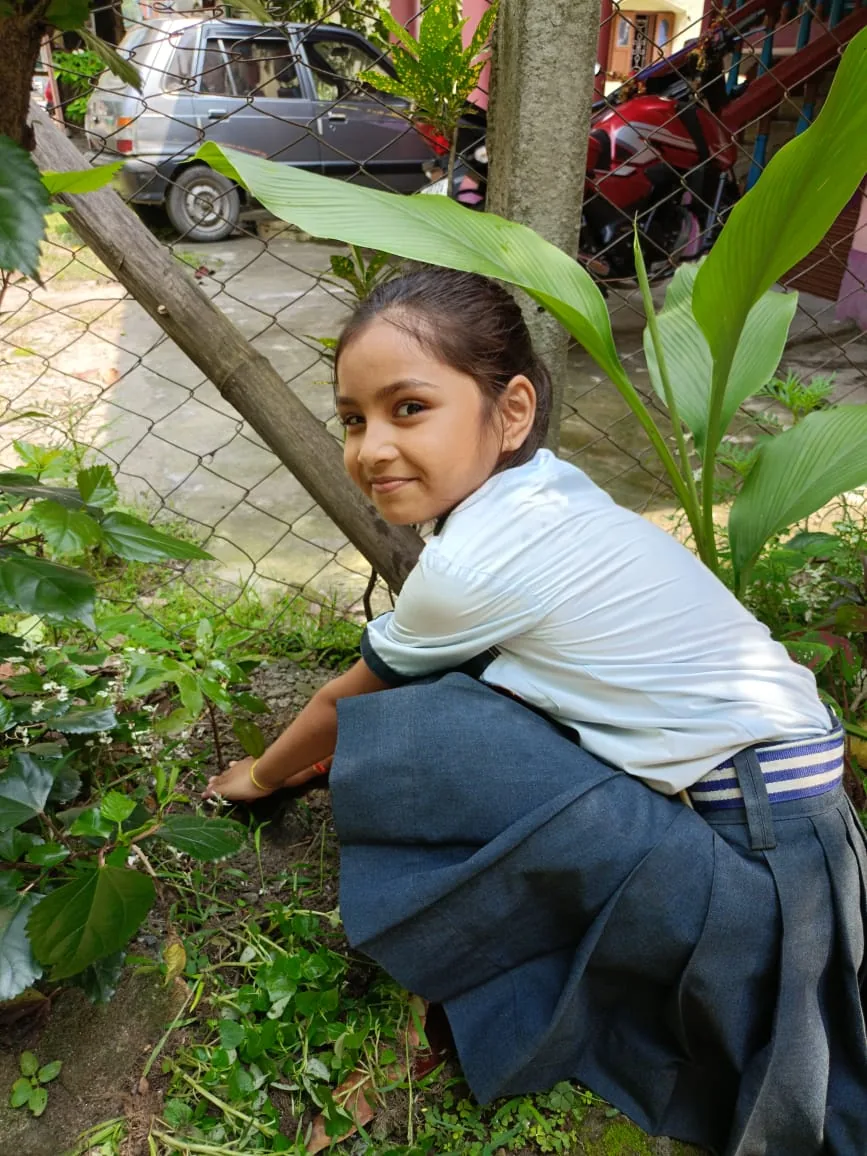 MGM pupil kneeling beside a plant and working with soil