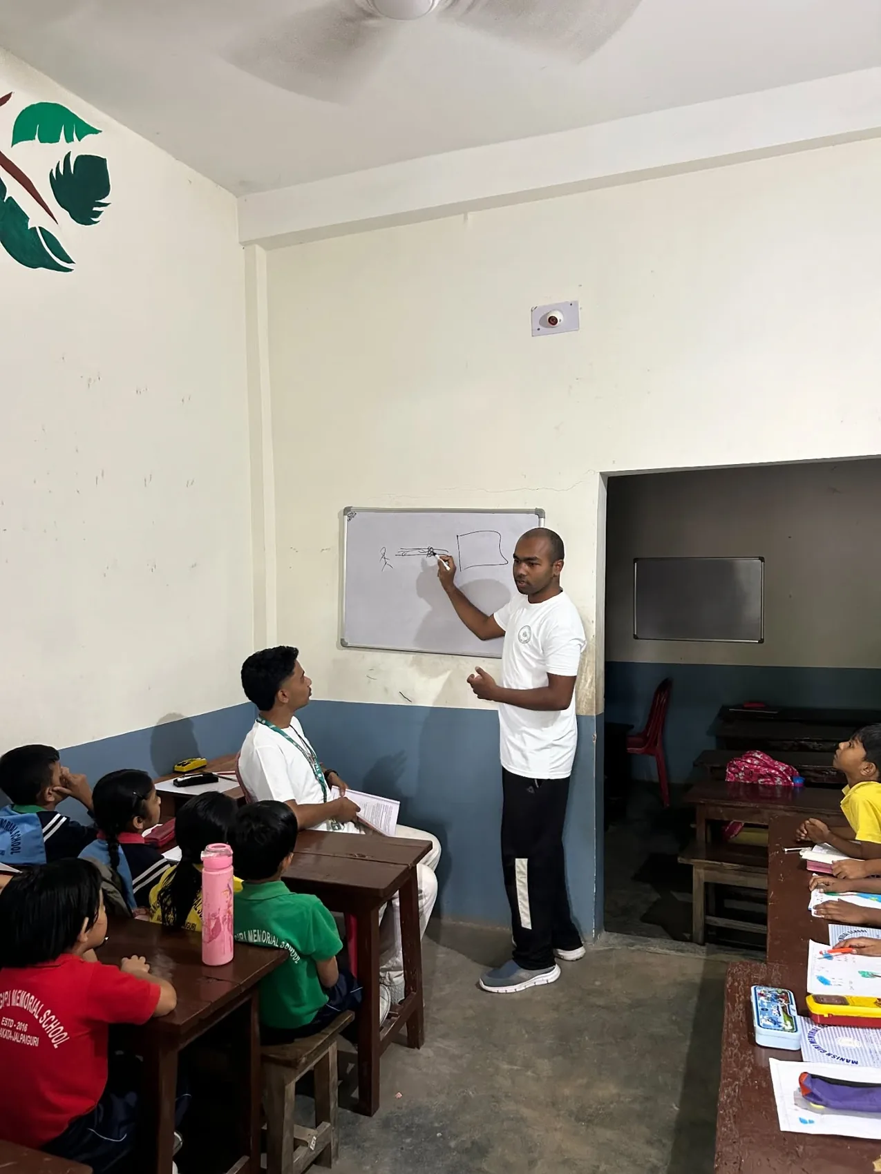 A teacher explaining a lesson at the whiteboard with students listening